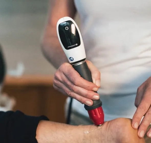Close-up of a Tubbs Chiropractic provider applying the shockwave therapy handpiece to a patient's ankle